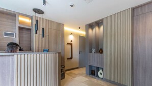 A reception area with a wooden reception desk, a wall-mounted light fixture, and a door leading to another room. - Jatisa 502 in Medell n (Medellín)