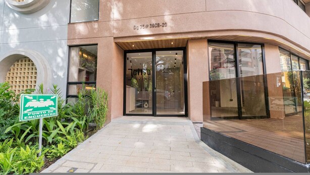 A building with a modern facade, a glass entrance, and a sign indicating a meeting point. - Jatisa 502 in Medell n (Medellín)