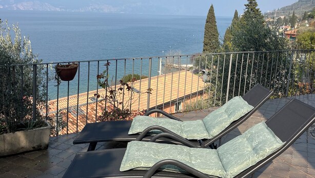 Terraço com cadeiras de descanso e vista para o litoral.