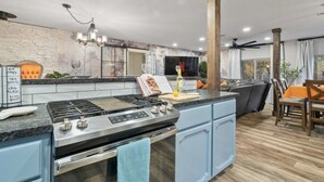 A modern kitchen with a central island, a built-in oven, and a dining area with a table and chairs. - Serene Creek Escape | SPA•Arcade•Yosemite•14 guest (Sonora)