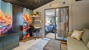 A room with a bed, a desk, a chair, a sofa, a bookshelf, and a sliding door leading to another room. - Family Game Retreat|Spa•Arcade•Pickleball•Yosemite (Sonora)