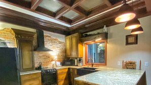 Una cucina con pavimento in legno, una grande isola, un muro in mattoni e luci a sospensione.