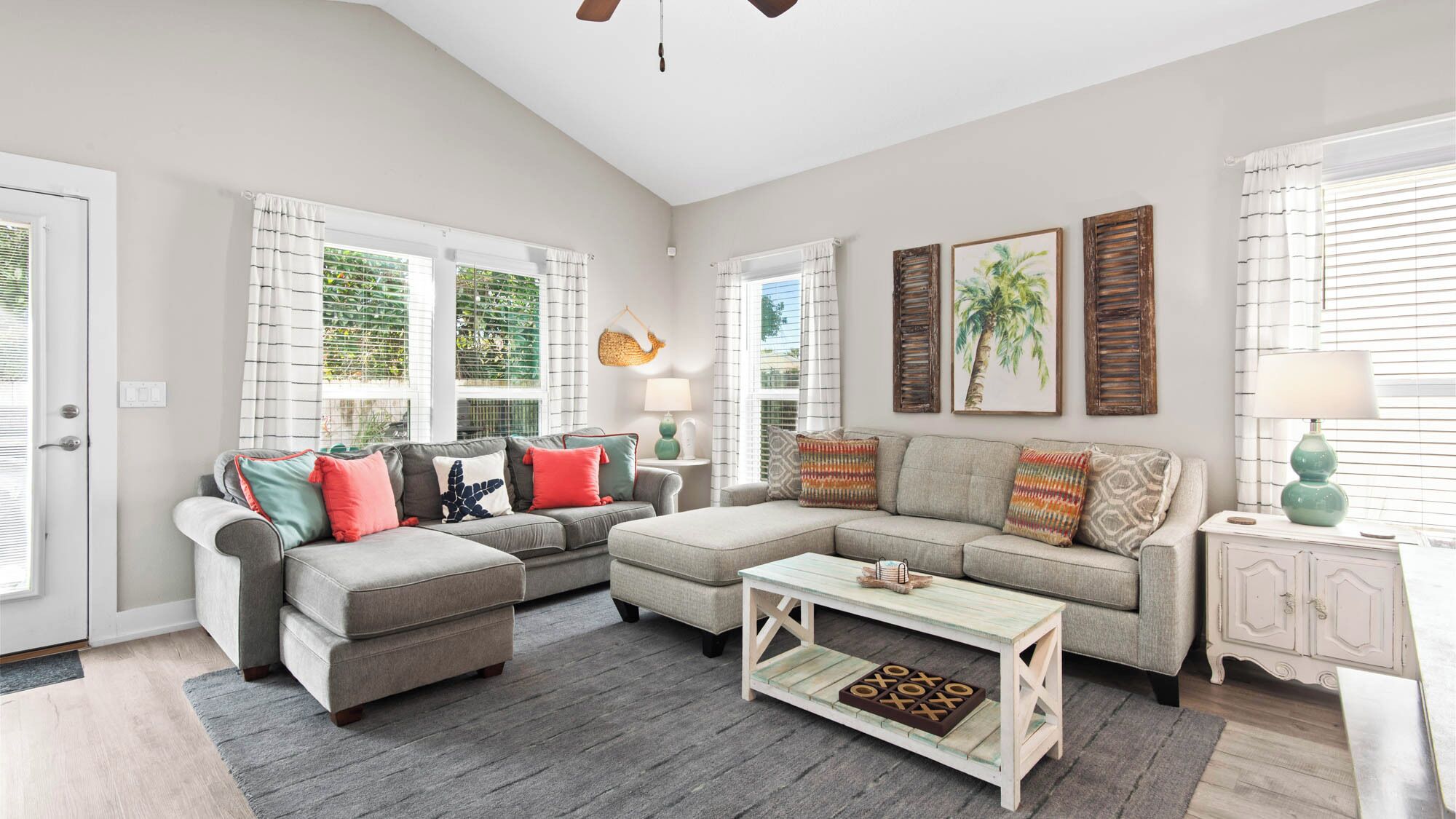 A spacious living room with a grey sectional sofa, a coffee table, and a white cabinet.