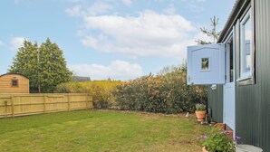 A backyard with a wooden fence, a metal water tank, and a potted plant. - Skye (Ludlow)