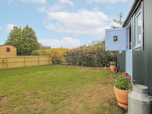 A backyard with a wooden fence, a metal water tank, and a potted plant. - Skye (Ludlow)