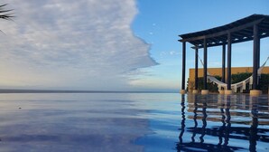 Ein Pool mit freiem Blick auf den Ozean, eine Holzpergola und eine Hängematte.