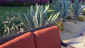Ein zweistöckiges Gebäude mit Terrasse, Säulen und Schwimmbad.