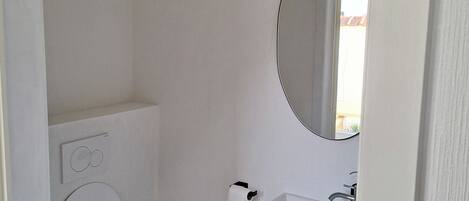 A small, modern bathroom with a toilet, a sink, and a mirror.