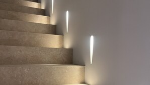 Uma escadaria com iluminação embutida e uma parede lisa.