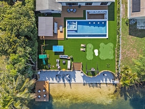 Eine Vogelperspektive auf ein modernes Haus mit Schwimmbad, Terrasse und Außenbereich mit Sitzgelegenheiten.