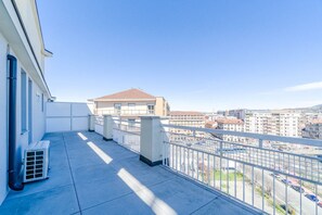 Ein Balkon mit Blick auf eine Stadtansicht, ein Gebäude mit rotem Dach und einem strahlend blauen Himmel.