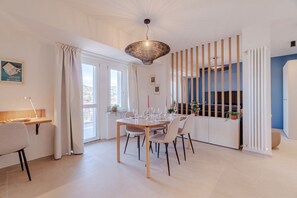 A dining area with a table set for four, a hanging light fixture, and a view through a window with vertical blinds. - Beautiful and bright apartment with a spacious terrace, tastefully furnished and perfect for three people. Located just meters from the Carducci metro station, the accommodation is also close to the hospital area (CTO, Molinette, Cellini), Valentino Park (Turin)