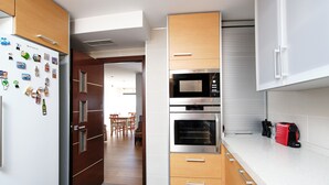 Eine moderne Küche mit Holzausstattung, einer eingebauten Mikrowelle, einem Backofen und einer Kaffeemaschine auf der Arbeitsfläche.