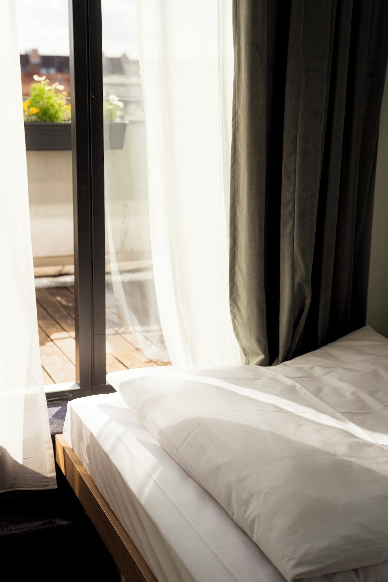 Un dormitorio con cama, una ventana con cortinas traslúcidas y vistas al exterior.