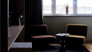 A modern living room with a sofa, a small table, and a window with a view of buildings. - ALPAMI Glockenbach  (Munich)