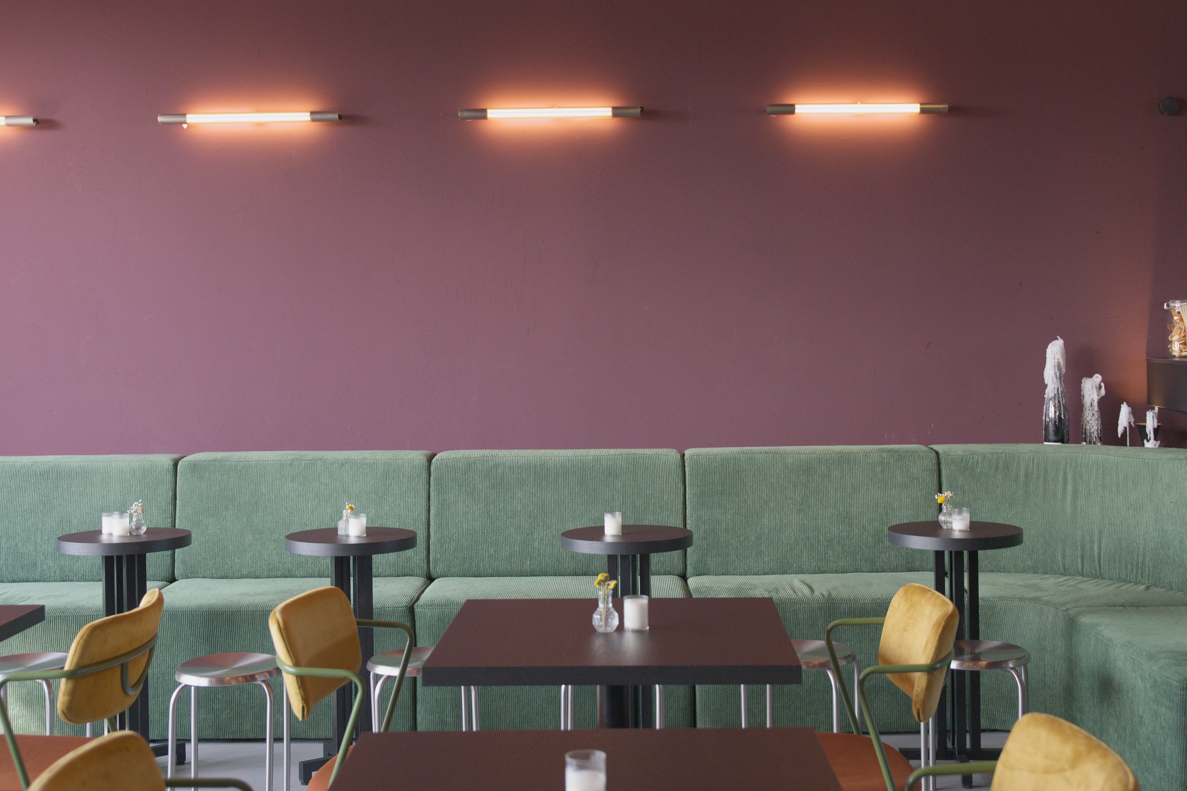 A restaurant interior with a green upholstered sofa, round tables, and chairs.