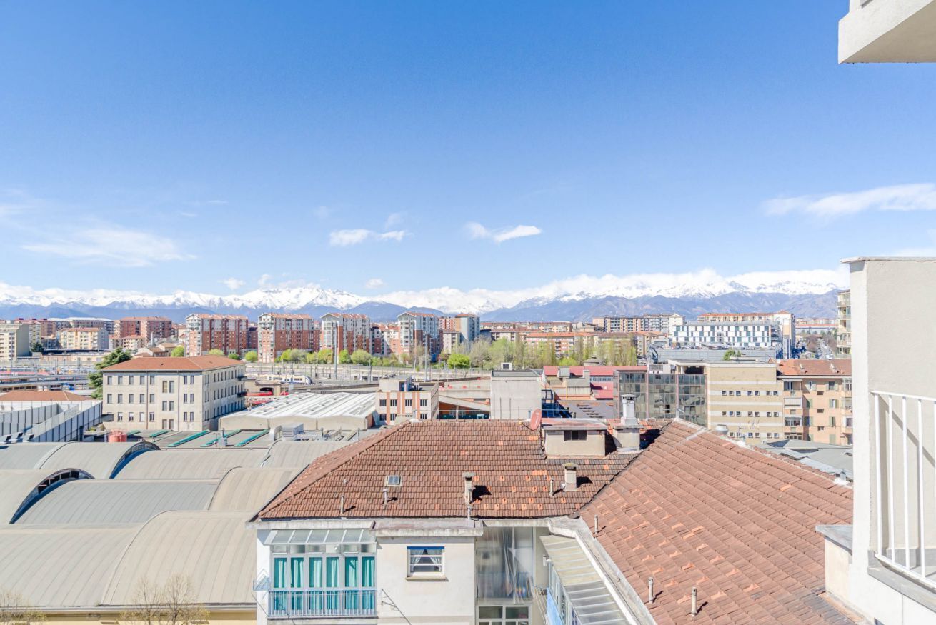 Un paisaje urbano con edificios, cielo despejado y montañas nevadas al fondo.