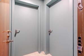 Ein Flur mit zwei geschlossenen Türen, jede mit Schlüsselloch und Griff.