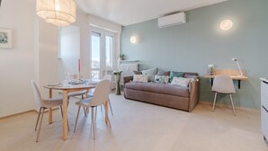 A modern living room with a dining area, a sofa, and a desk. - This large studio apartment is ideally located for exploring Turin, with easy access to the subway, allowing you to reach the city center in just a few minutes and the lively San Salvario neighborhood in even less time. Just steps from Parco del Po, the  (Turin)