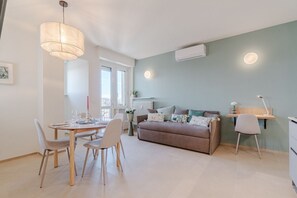 Ein modernes Wohnzimmer mit Essbereich, einer Couch und einem Schreibtisch.