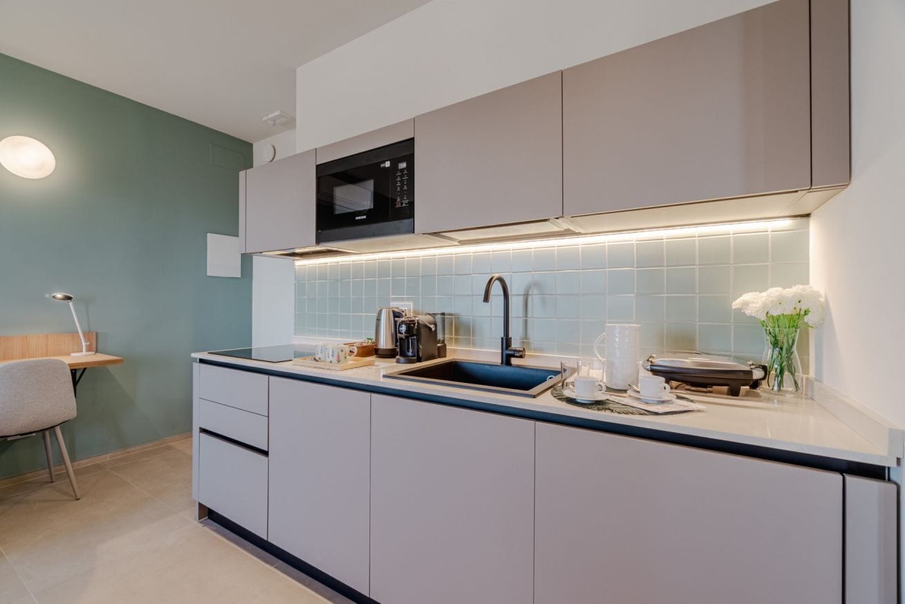 Eine moderne Küche mit Einbau-Mikrowelle, Spüle und einer Arbeitsfläche mit Wasserkocher und Tassen.