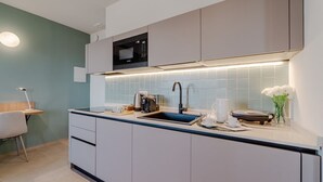 A modern kitchen with a built-in microwave, a sink, and a countertop with a kettle and cups. - This large studio apartment is ideally located for exploring Turin, with easy access to the subway, allowing you to reach the city center in just a few minutes and the lively San Salvario neighborhood in even less time. Just steps from Parco del Po, the  (Turin)