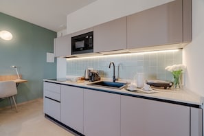 Eine moderne Küche mit Einbau-Mikrowelle, Spüle und einer Arbeitsfläche mit Wasserkocher und Tassen.