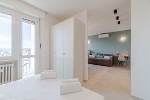 Ein modernes Hotelzimmer mit einem großen Bett, einem Balkon, einer Sitzecke mit einer Couch und einem Schreibtisch.
