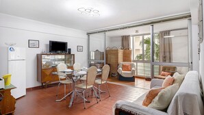 Una sala moderna con comedor, televisor y puerta corrediza de vidrio al exterior.