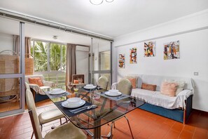 A dining area with a glass table, chairs, and a sofa with cushions. - Apartment 'Vasco Da Gama' with Wi-Fi and Air Conditioning (Quarteira)