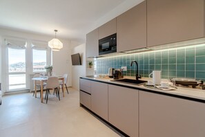 Eine moderne Küche mit Essbereich, einem Flachbildfernseher und Blick durch das Fenster.