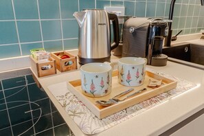 A kitchen counter with a coffee maker, two cups, a tray with utensils, and a kettle. - A comfortable studio apartment with a terrace offering all the amenities needed to accommodate up to three guests. Conveniently located, very close to the metro, it allows you to reach the city center in just six minutes and the San Salvario neighborhood (Turin)