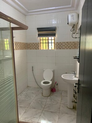 A bathroom with a toilet, sink, and window. - FFA Resort Center (Akure)