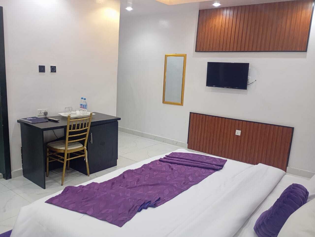 Una camera d'albergo con un letto, una scrivania, una sedia, una TV e uno specchio.