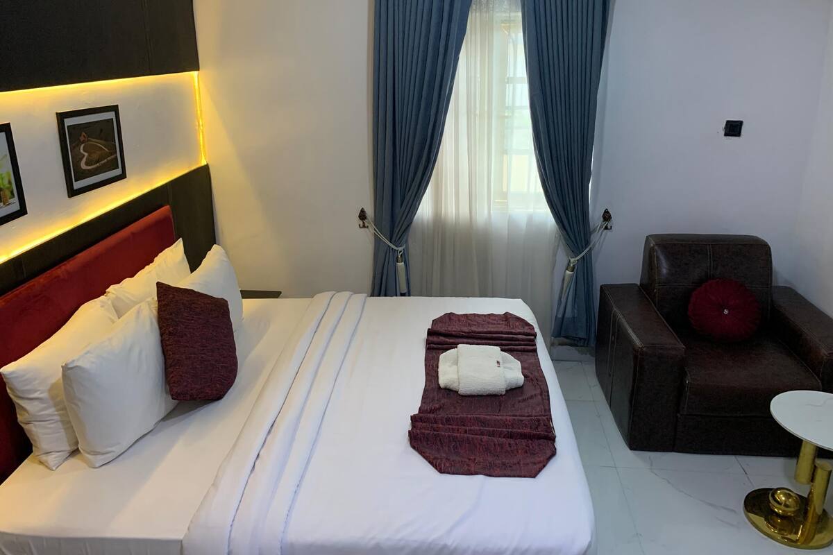 Ein Hotelzimmer mit Bett, Stuhl, Tisch und einem Vorhangfenster.