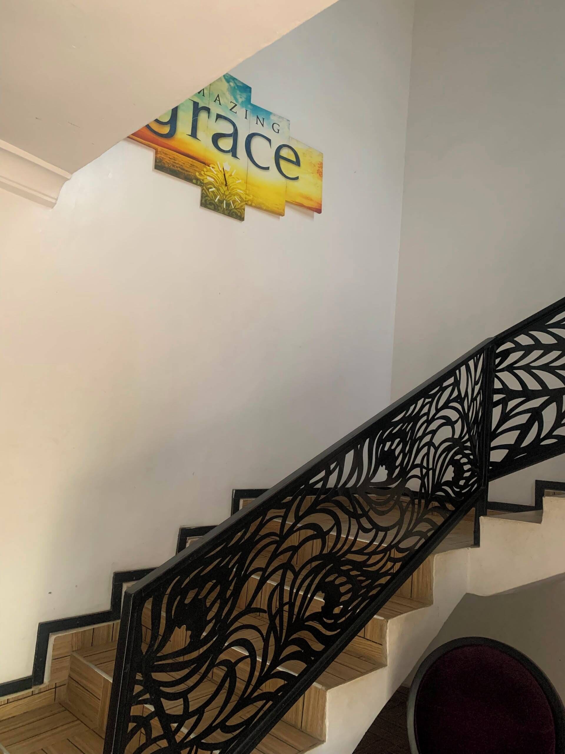 Una escala amb barana decorativa i un senyal damunt.