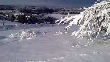 A snowy landscape with a clear view of a valley and distant hills.