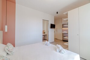 A modern hotel room with a bed, a TV, a wardrobe, and a bathroom visible through an open door. - Elegant studio apartment in a very convenient location, right in front of the metro station: in just 6 minutes you'll be downtown, and even faster to the lively San Salvario neighborhood. The apartment is just steps from the Po River Park, the Lingotto e (Turin)