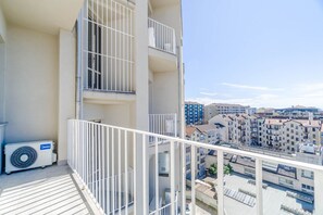 A balcony with a white railing, an air conditioning unit, and a view of a residential area with multiple buildings. - Elegant studio apartment in a very convenient location, right in front of the metro station: in just 6 minutes you'll be downtown, and even faster to the lively San Salvario neighborhood. The apartment is just steps from the Po River Park, the Lingotto e (Turin)