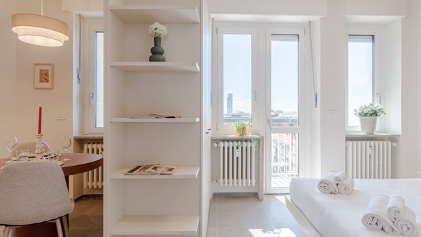 Moderni hotellihuone, jossa on ruokailutila, parveke, jolta on näkymä, ja siististi pedattu sänky.
