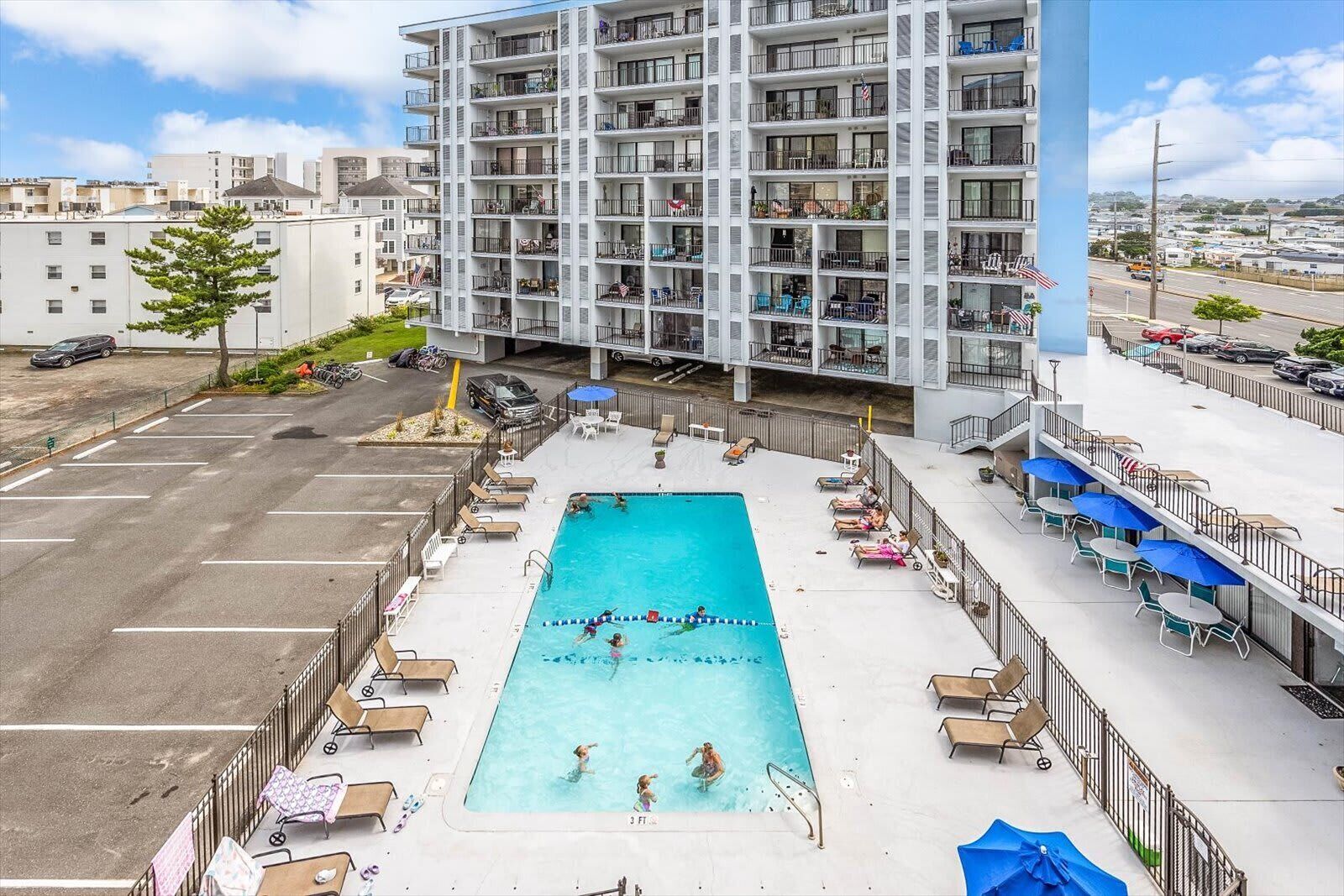 Un hotel de varios pisos con piscina en la azotea, zona de estar al aire libre y vistas a la ciudad.