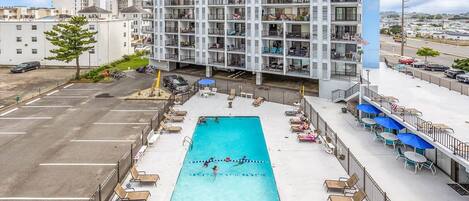 Un hotel de varios pisos con piscina en la azotea, zona de estar al aire libre y vistas a la ciudad.