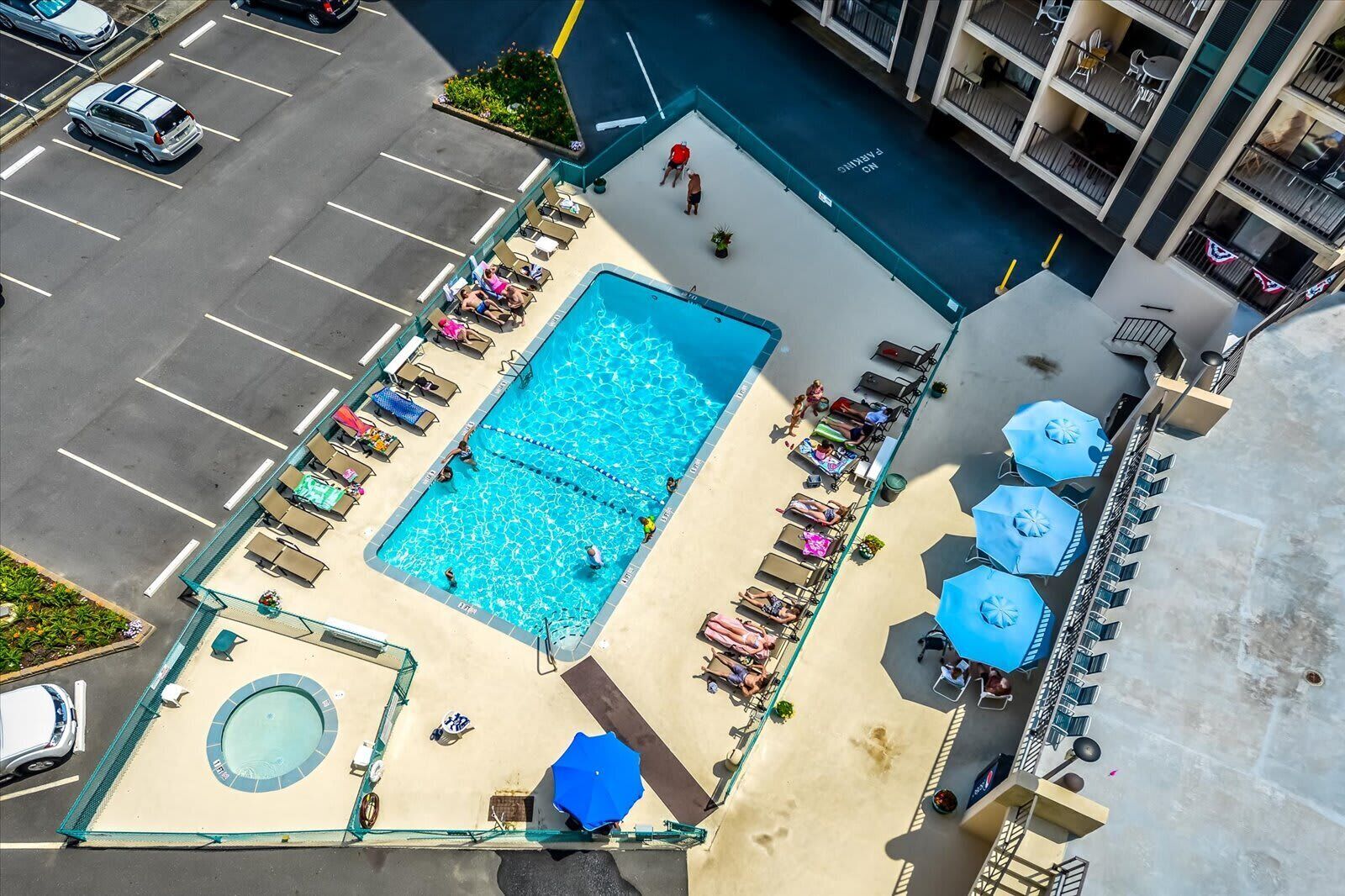 Eine Vogelperspektive auf ein Hotel mit Schwimmbad, Liegestühlen und einer kleinen Whirlpool.