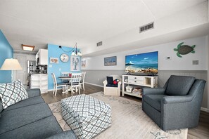 Een woonkamer met een bank, fauteuil, eettafel en een televisie.