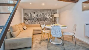 Ein modernes Wohnzimmer mit einer Couch, einem Esstisch, Stühlen und einer Stadtszenen-Wandmalerei.