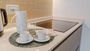 Een keukentablet met een koffiezetapparaat, twee kopjes, een glas en een placemat.