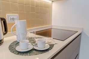 Eine Küchenarbeitsplatte mit einer Kaffeemaschine, zwei Tassen, einem Glas und einer Unterlage.