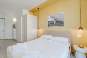 A hotel room with a bed, a bedside table, a wall-mounted picture, and a small stool with a book. - A charming studio apartment in an extremely convenient location, with the subway practically on your doorstep: Turin city center can be reached in about six minutes, while the San Salvario neighborhood is even closer. The apartment is a short distance fr (Turin)