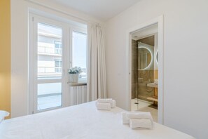 Ein Hotelzimmer mit Bett, Bad mit Dusche und Blick auf Gebäude.
