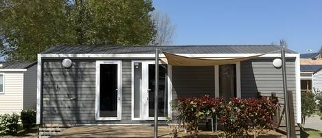 Une maison mobile de plain-pied dotée d’un porche couvert, d’une petite terrasse et d’une plaque portant le numéro « 3016 ».